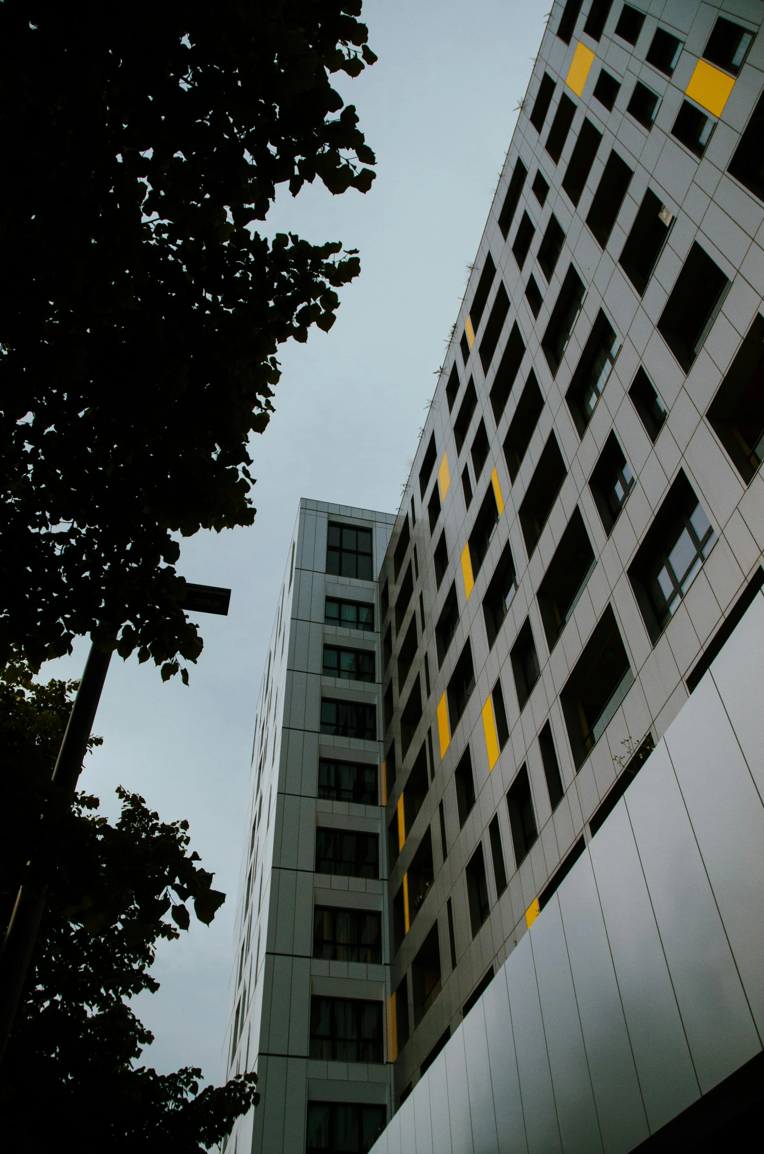 a tall building next to a large building under a cloudy sky