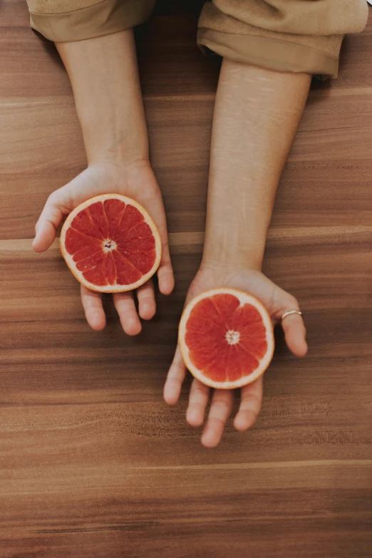 a person holding gfruit cut in half in their hands