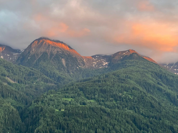 the view of several mountain tops and trees in front of them