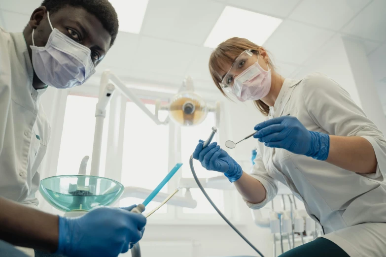 two dentists in masks and protective equipment examining tooth paste