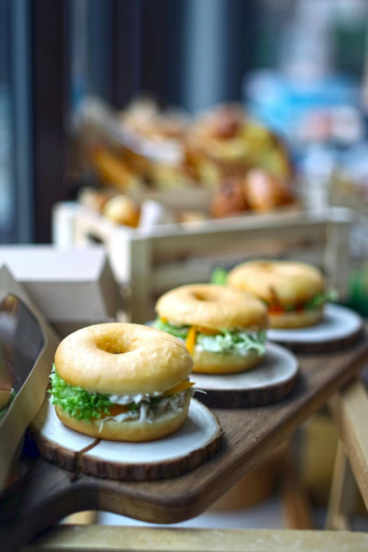 many burgers sitting on wooden boards with a tray in front