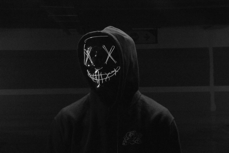 a person in a dark hooded hoodie with white face paint