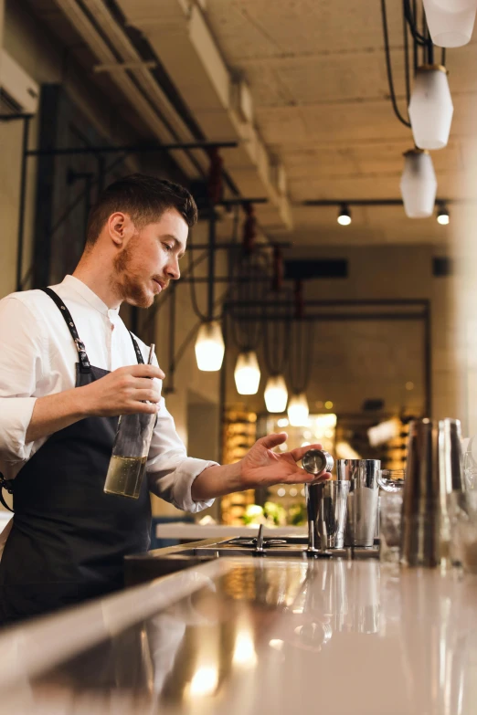 a man pouring drinks into a cup in the kitchen