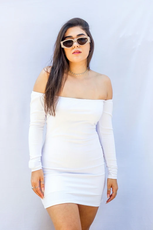 a woman in sunglasses and a white dress posing for a po