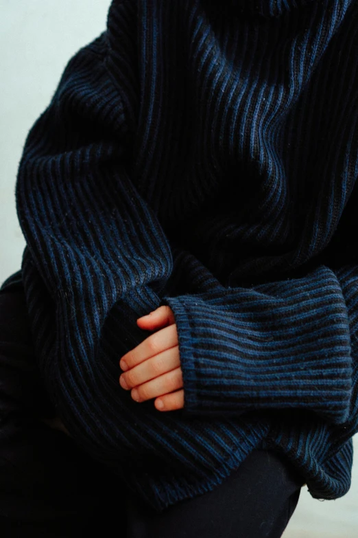 a person in an oversize black and blue sweater