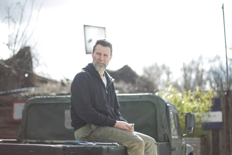 a man sitting on a military vehicle outside