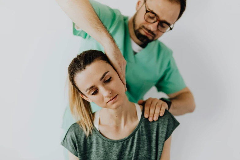 a woman being examined by a man in a green shirt