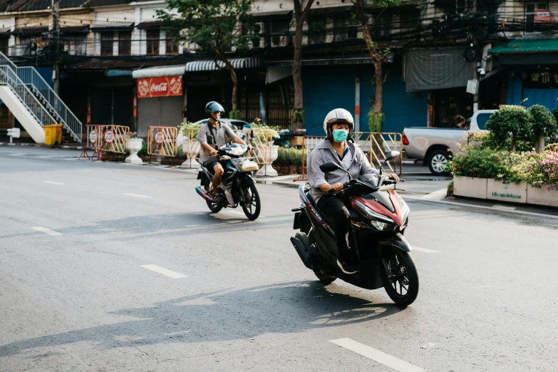 two men wearing face masks and sitting on motorcycles