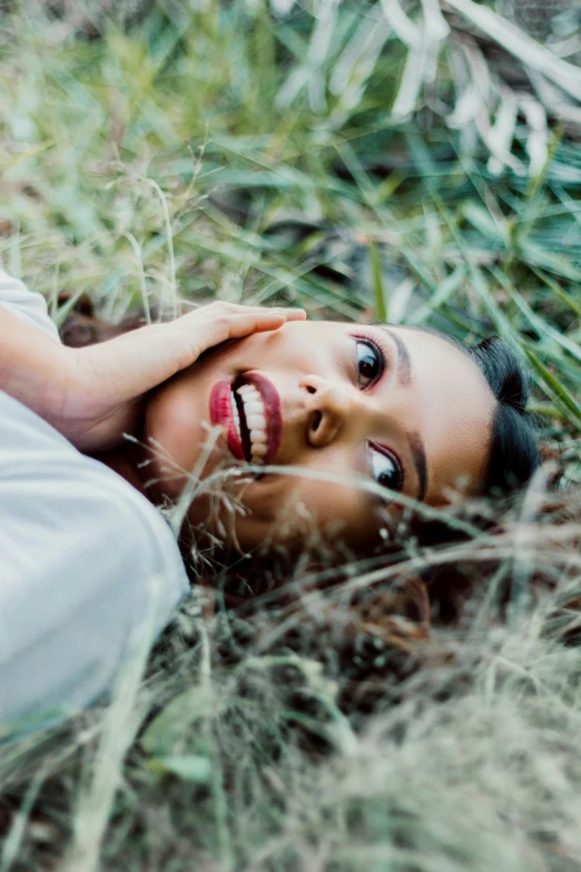 a girl looks upwards from behind in the tall grass