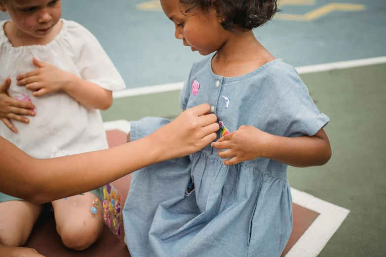 two little girls, one playing with her fingers and tying soing to another