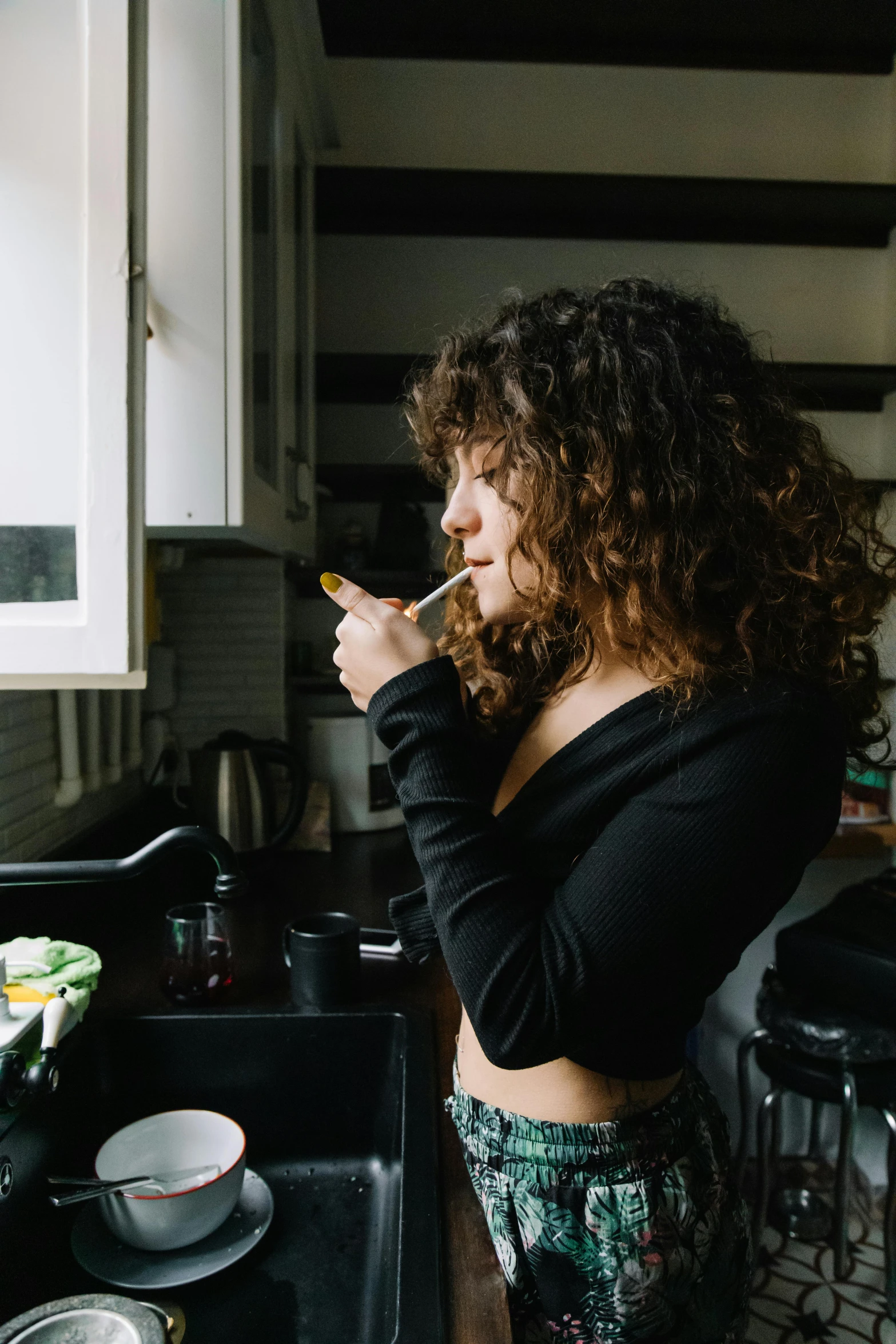 a woman standing next to a kitchen sink brushing her teeth