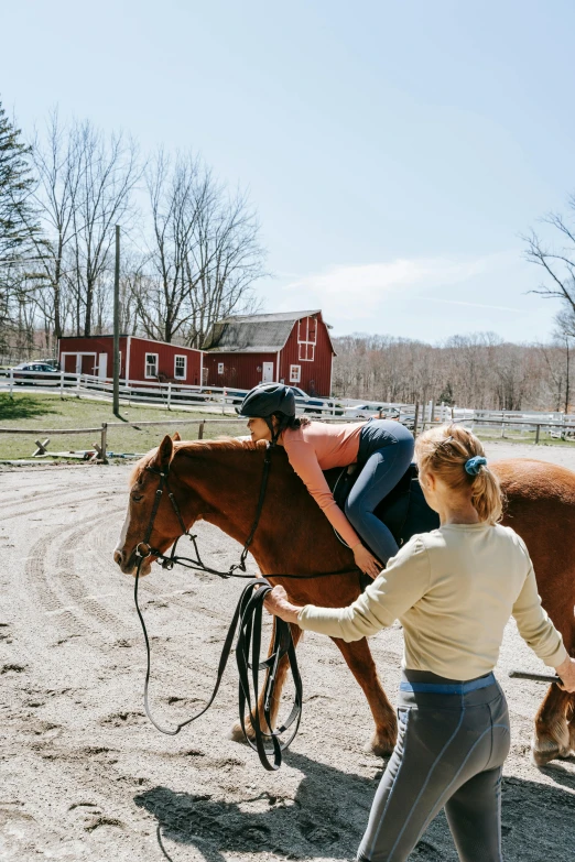 a woman guiding a horse around a corral