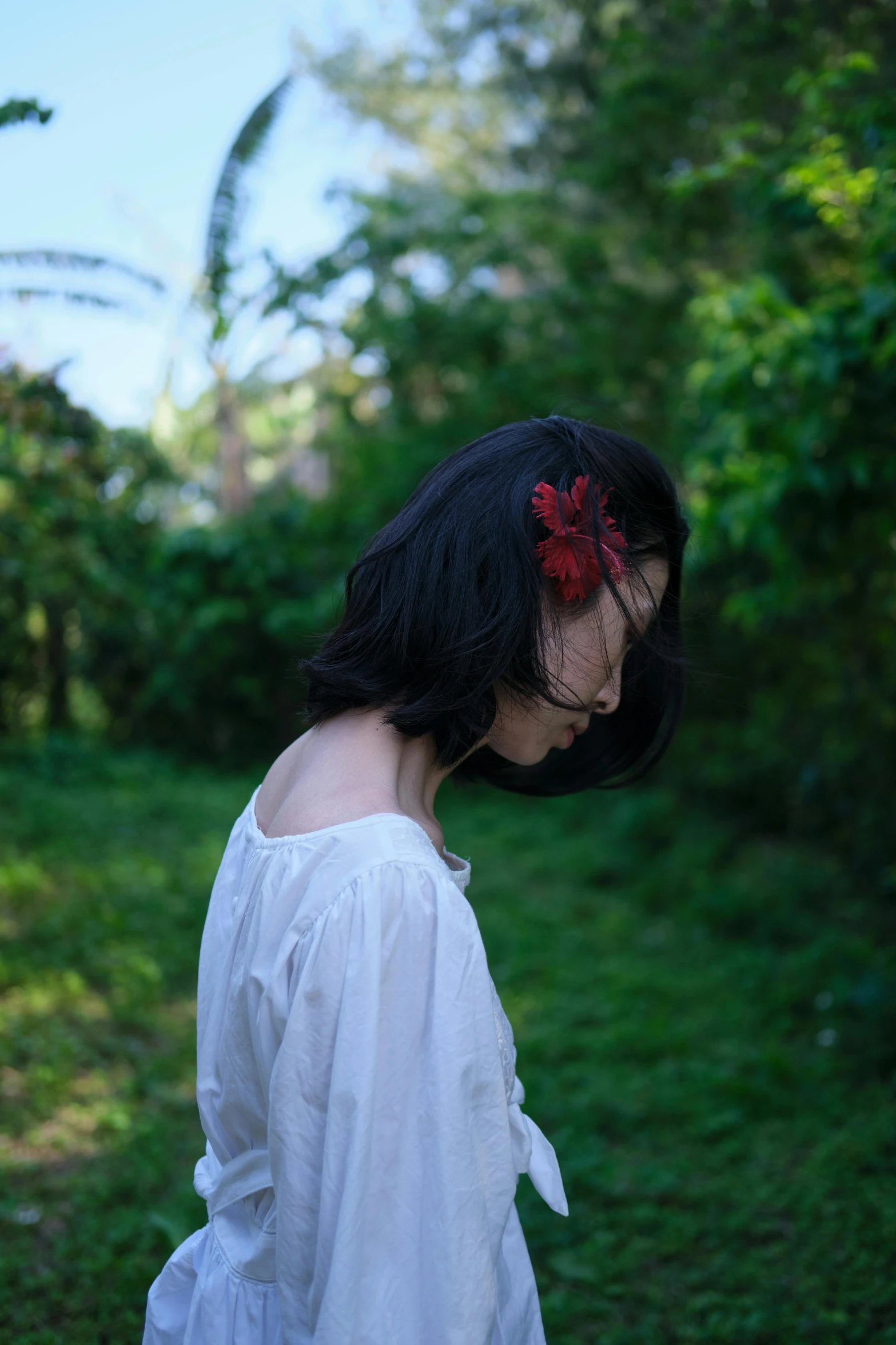 a woman in white is standing near a bush