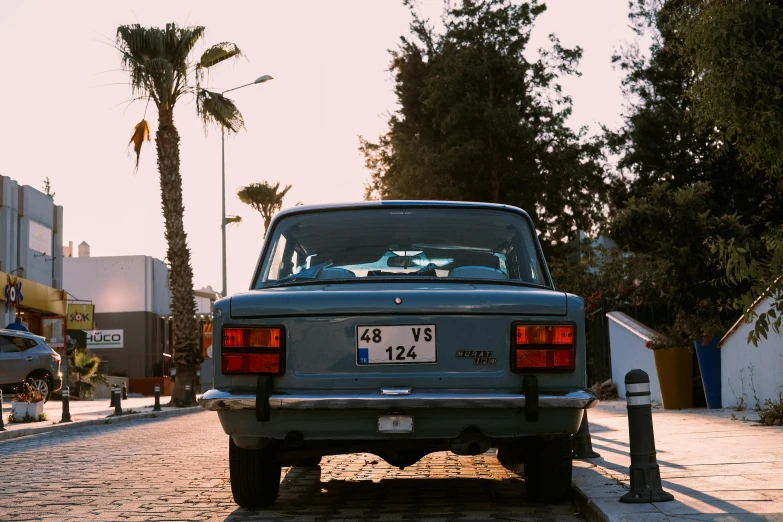 an old car parked on the street next to a tree