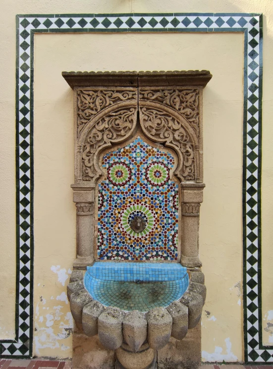 a fancy wall fountain in the middle of an outdoor space