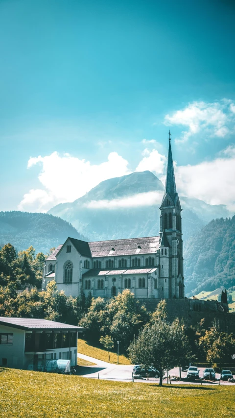 a church on top of a green hill in front of some mountains