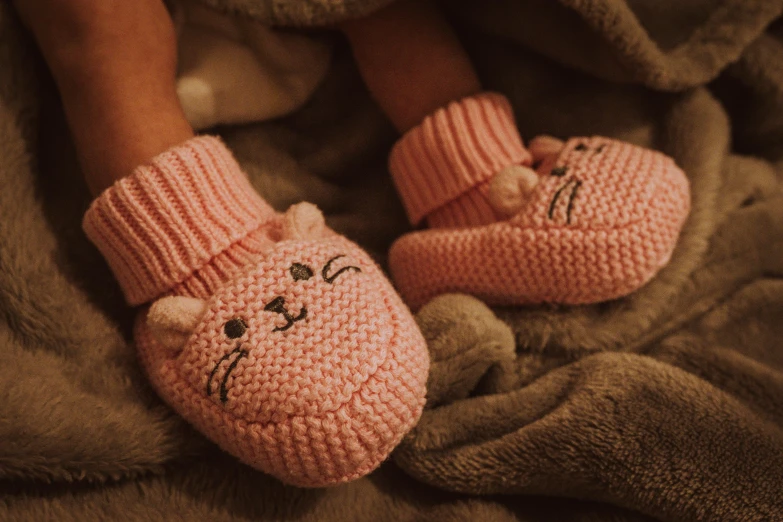 a person sitting in a bed with pink crocheted slippers