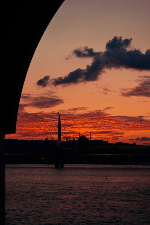 an arch with a building and sunset in the background