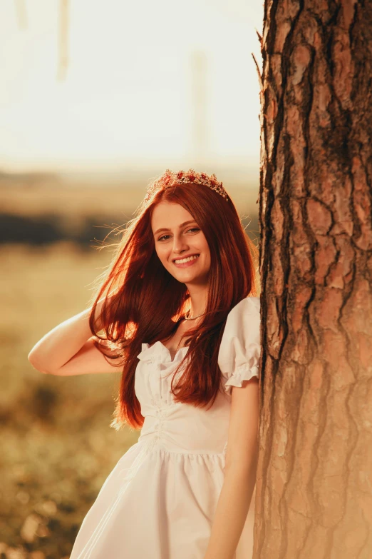 a young woman leans against a tree trunk