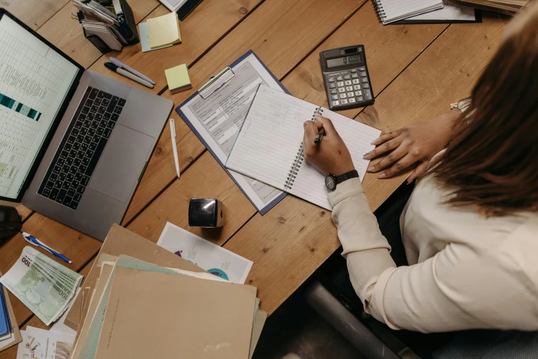 a woman is working at a table with lots of papers