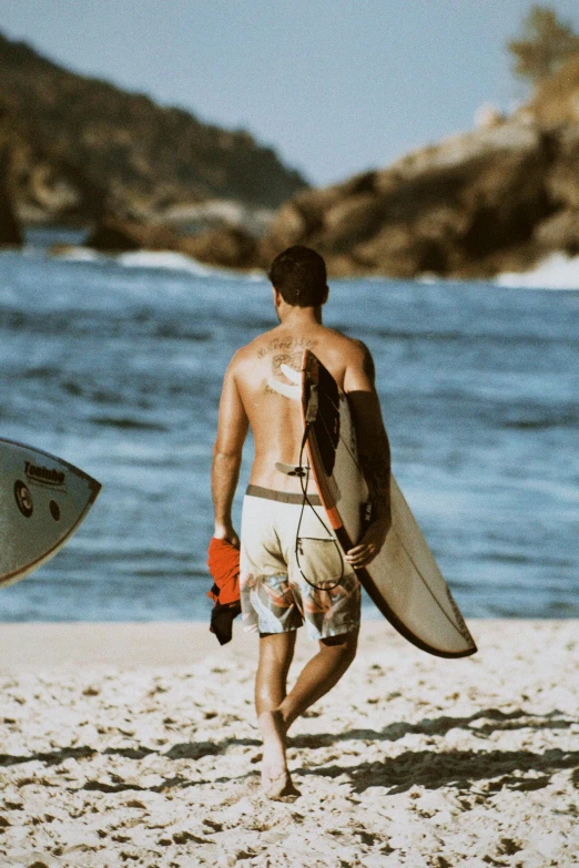 a man holding a surfboard walking on the beach