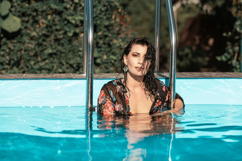 a beautiful woman floating in a pool of water wearing a floral bathrobe