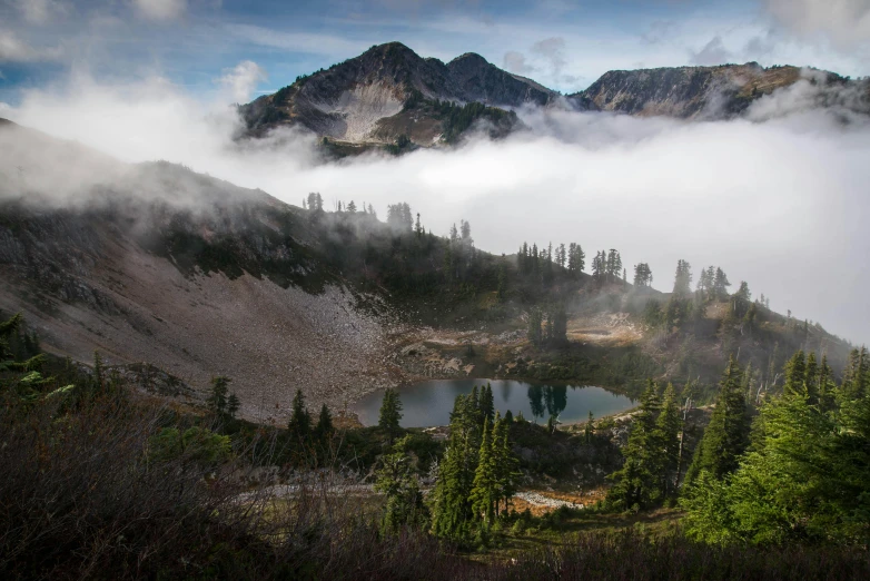 a mountain landscape with a small lake and mountains in the background