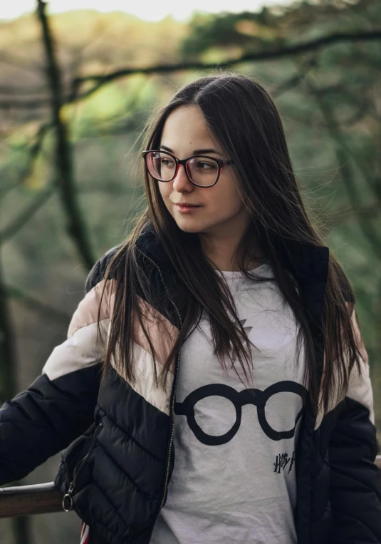 a young woman in glasses standing next to a tree
