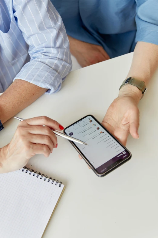 two people working with a smart phone on a table