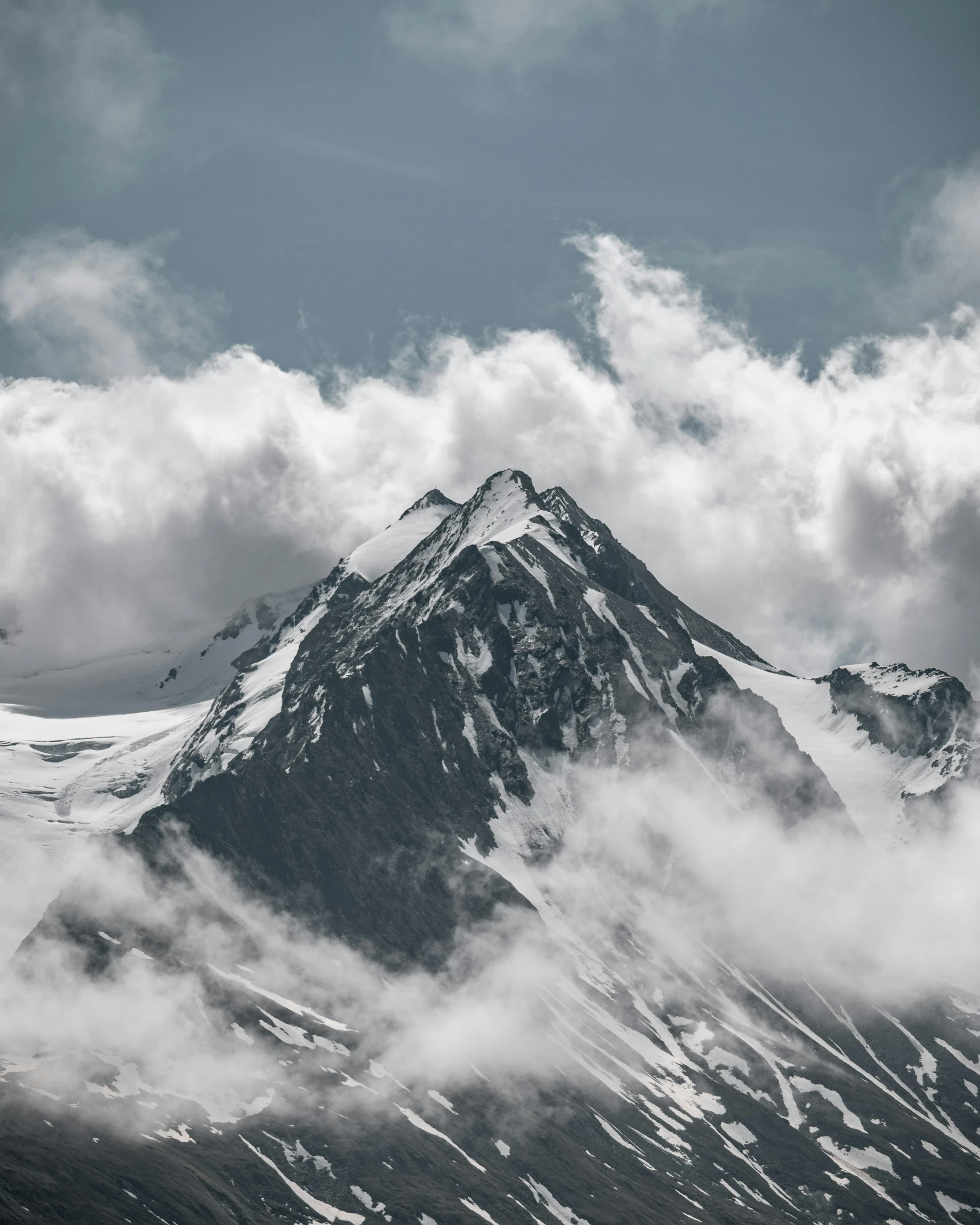 there is a snow covered mountain on a cloudy day