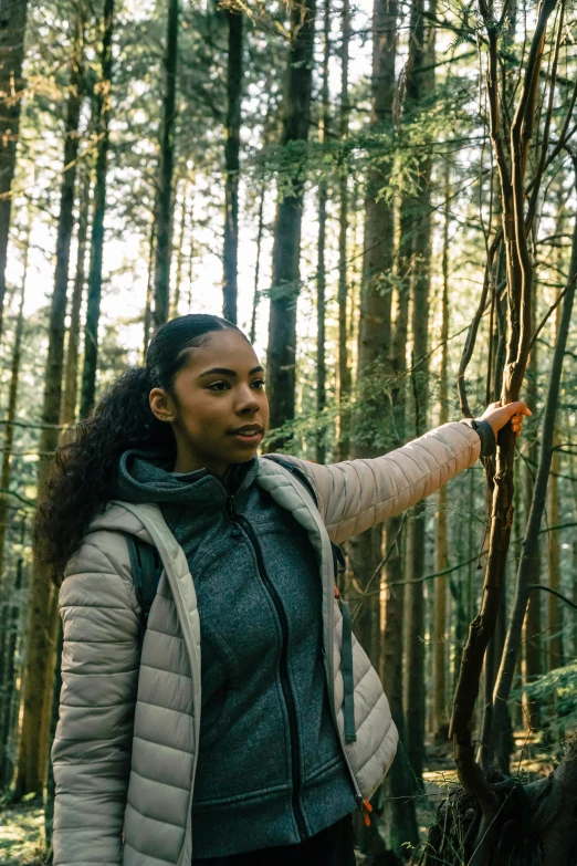 a woman holds out an object in a forest