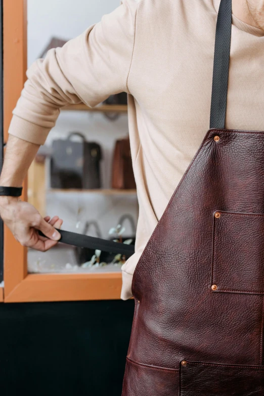 a man holds a large knife and is wearing a leather apron