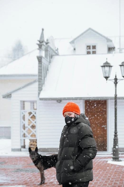 a man in black jacket standing in snow with his dog