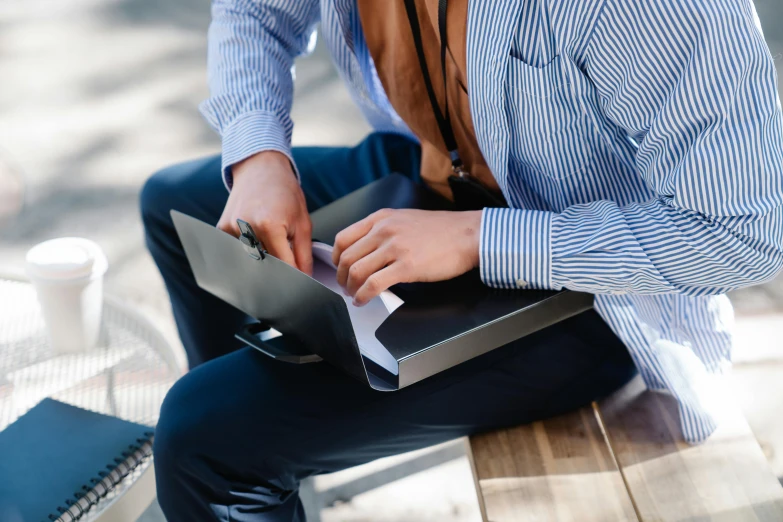 person holding binder sitting on wooden bench