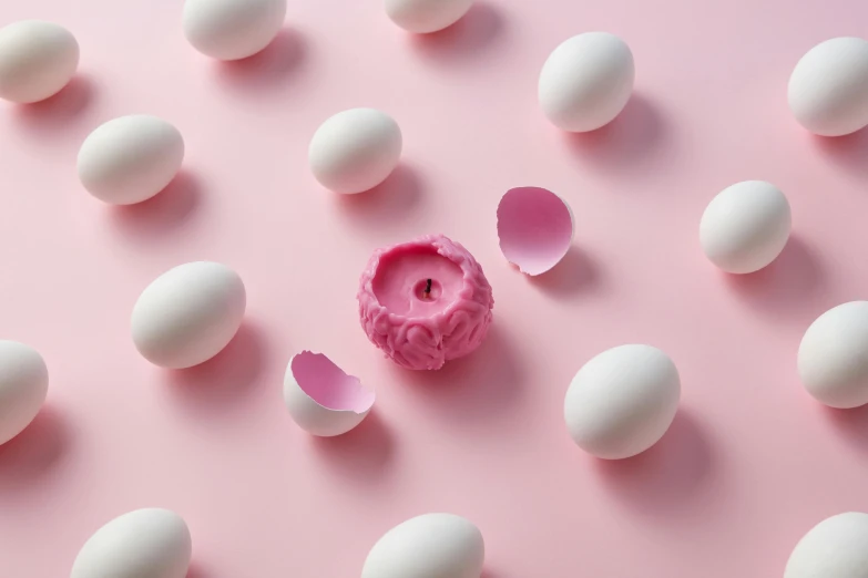 several eggs and a pink flower on a pink surface