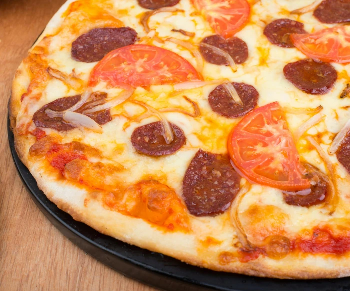 the small pizza is made with tomato, cheese and sausage