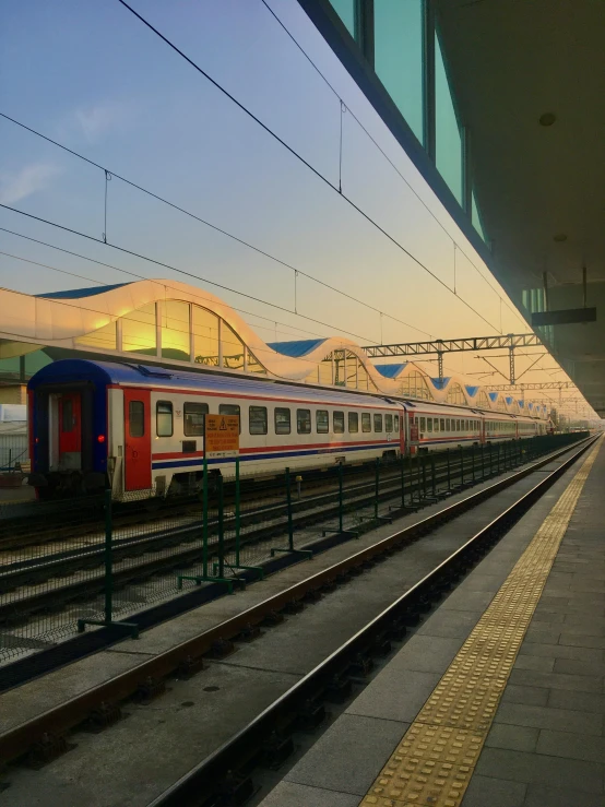 a passenger train sits near the station with its lights on