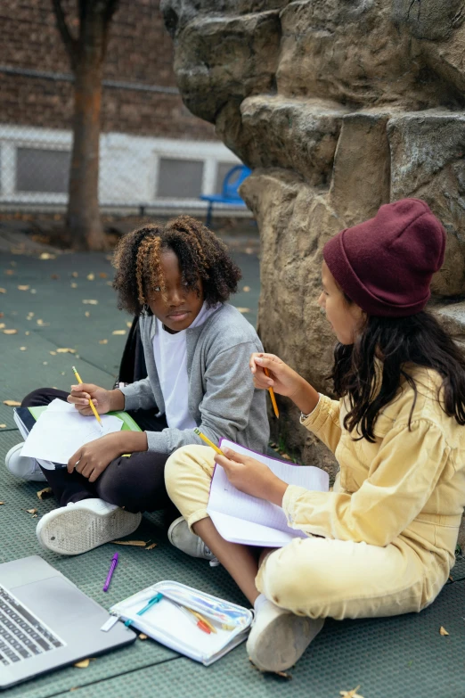 two girls sitting on the ground doing homework