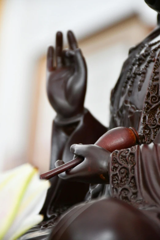 a buddha statue with a wooden spoon in his hands