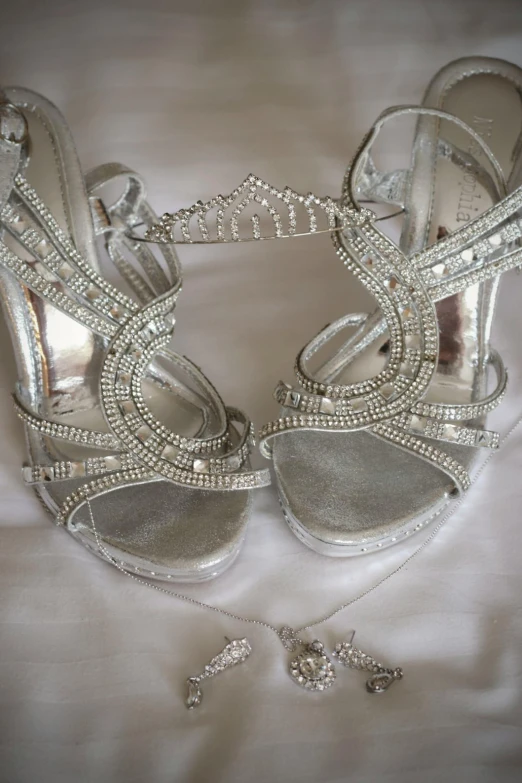 the bride's silver heels and accessories are on a white sheet