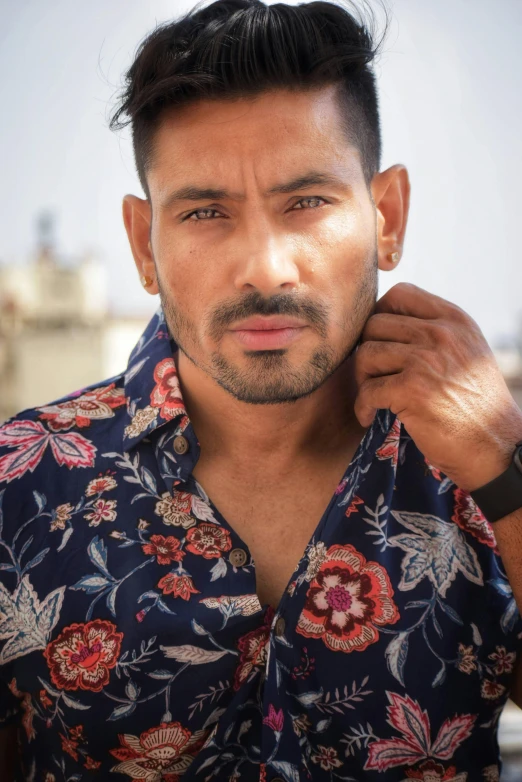 a man with a short black hair standing and looking at the camera