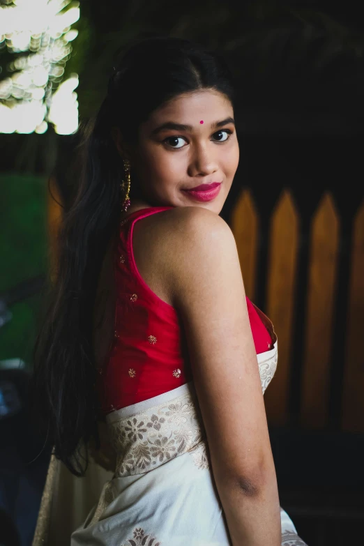 a young indian girl in white and red poses for the camera