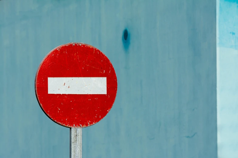 an upside down traffic sign next to a blue wall