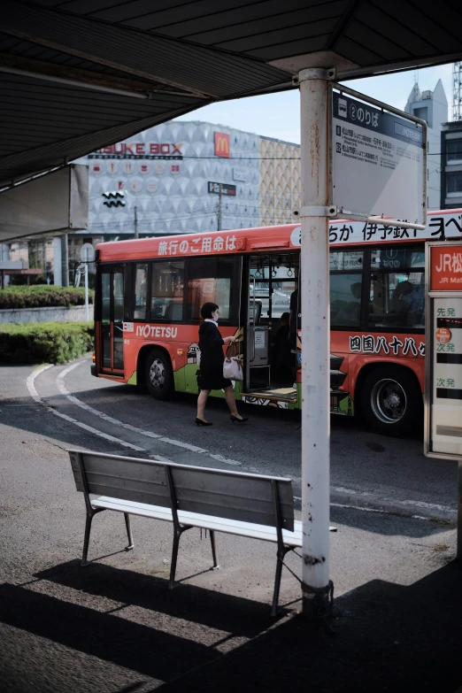 a red bus parked next to a man in black shirt