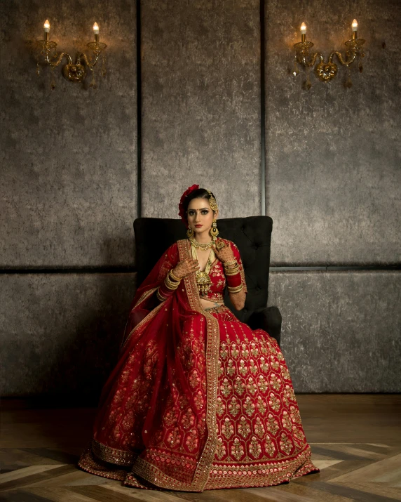 a woman sitting on top of a chair wearing a red dress