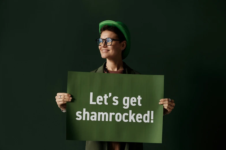 woman holding a green sign saying let's get shamrock -cked