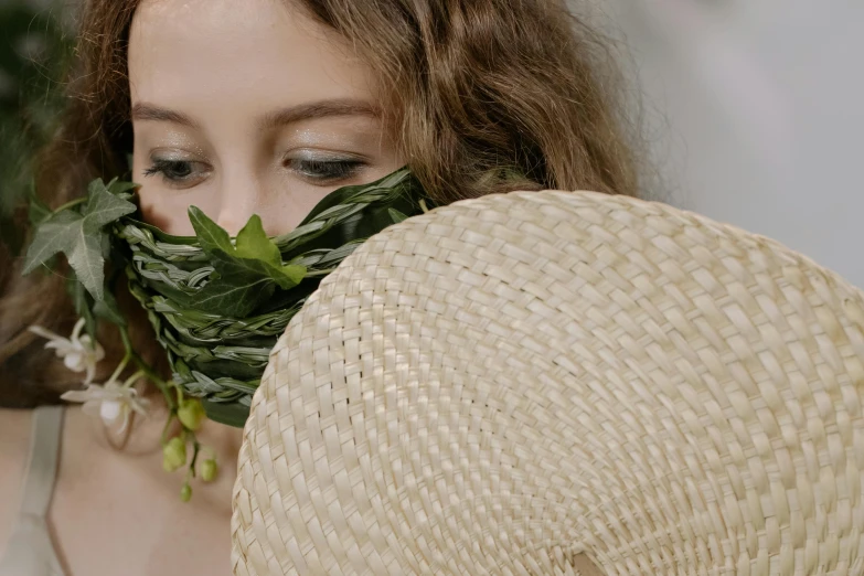 a woman with long hair holds a piece of leaves above her face