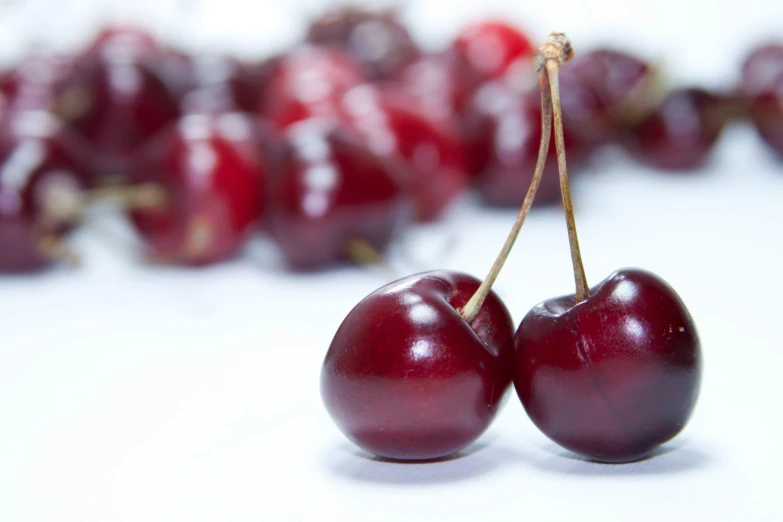 two cherries sitting on top of each other in front of red cherries