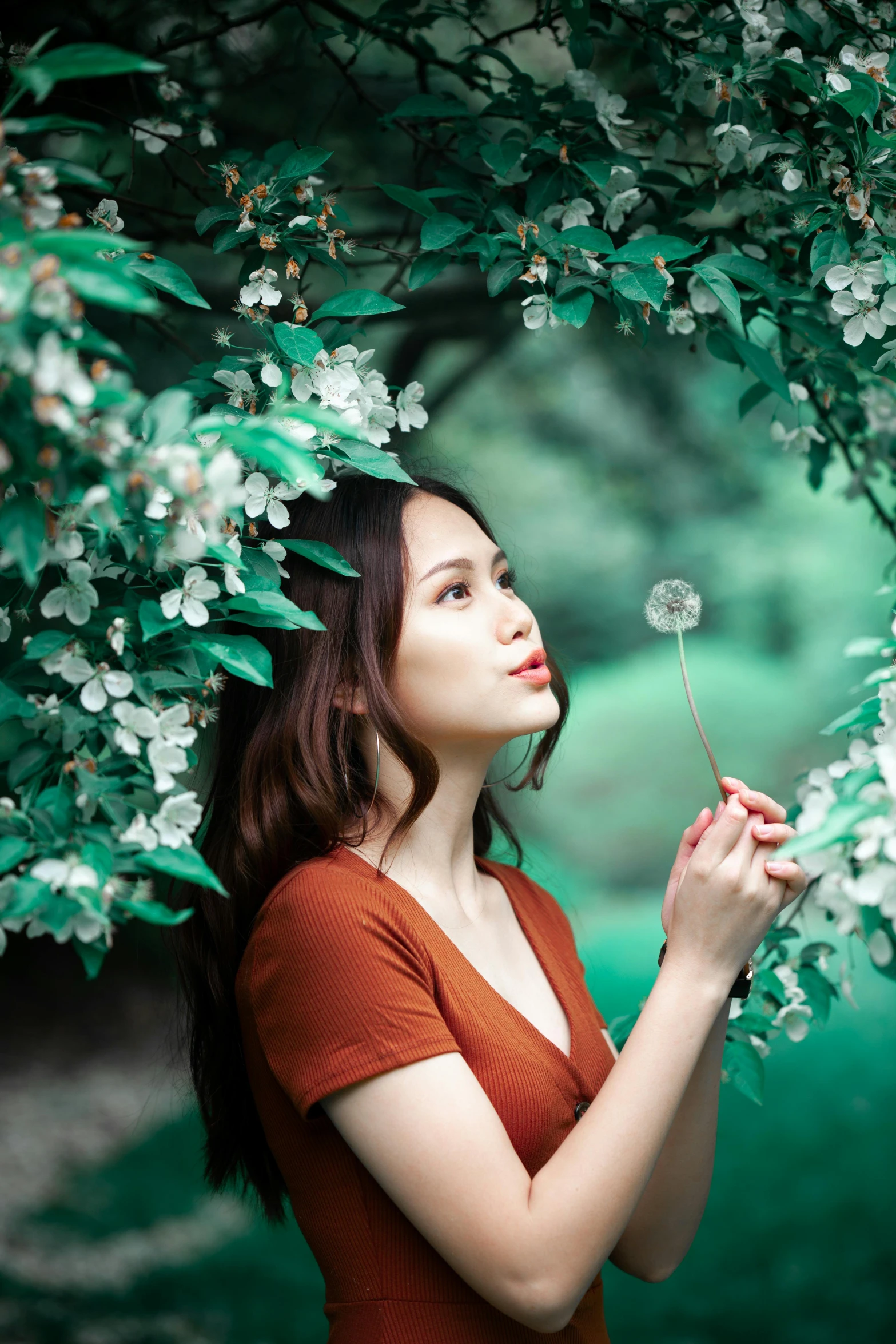 a woman in a red dress blowing on a flower