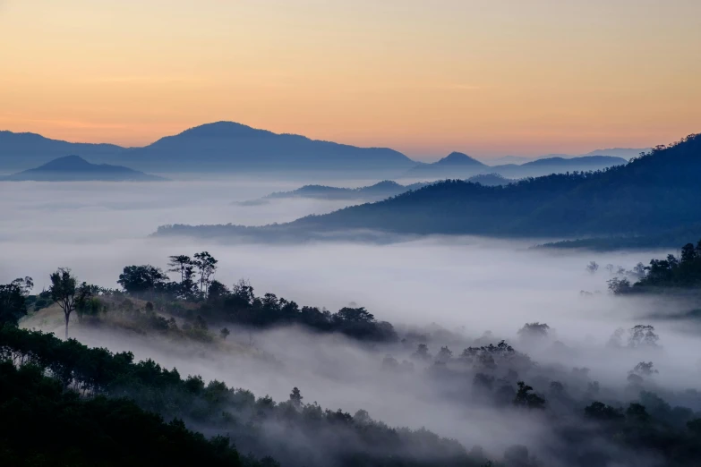 a sunset view of fog at the top of a mountain